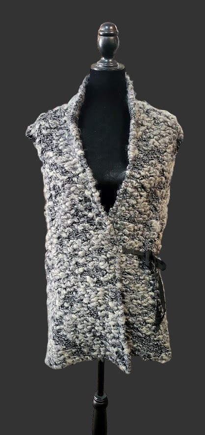 Textured gray vest on a mannequin in a store setting with clothing racks and displays in the background.