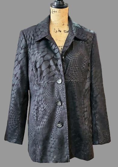 Black textured coat on a mannequin in a store setting with various items in the background.