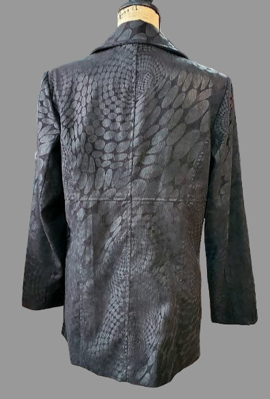 Black leather jacket on a mannequin in a store setting with various clothing items in the background.