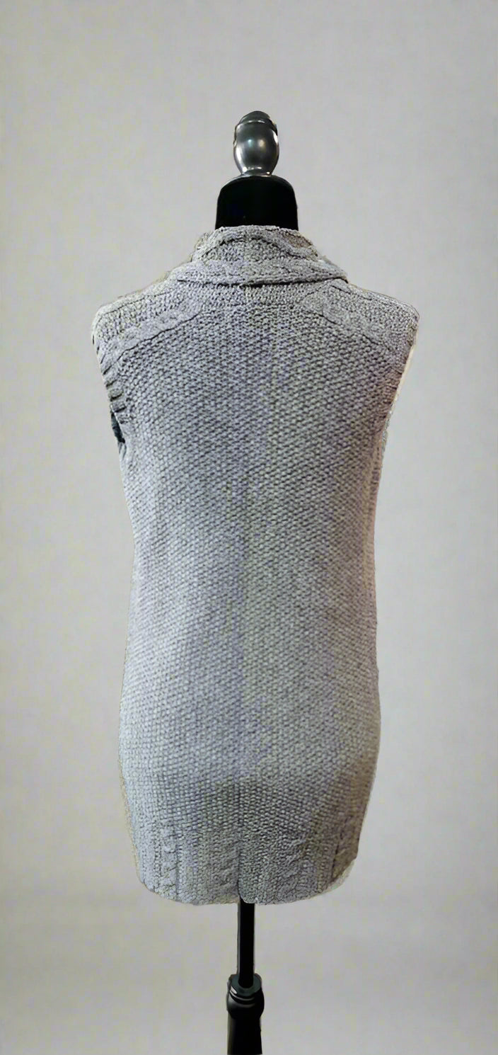 Gray vest on a mannequin in a store setting with racks of clothes in the background.