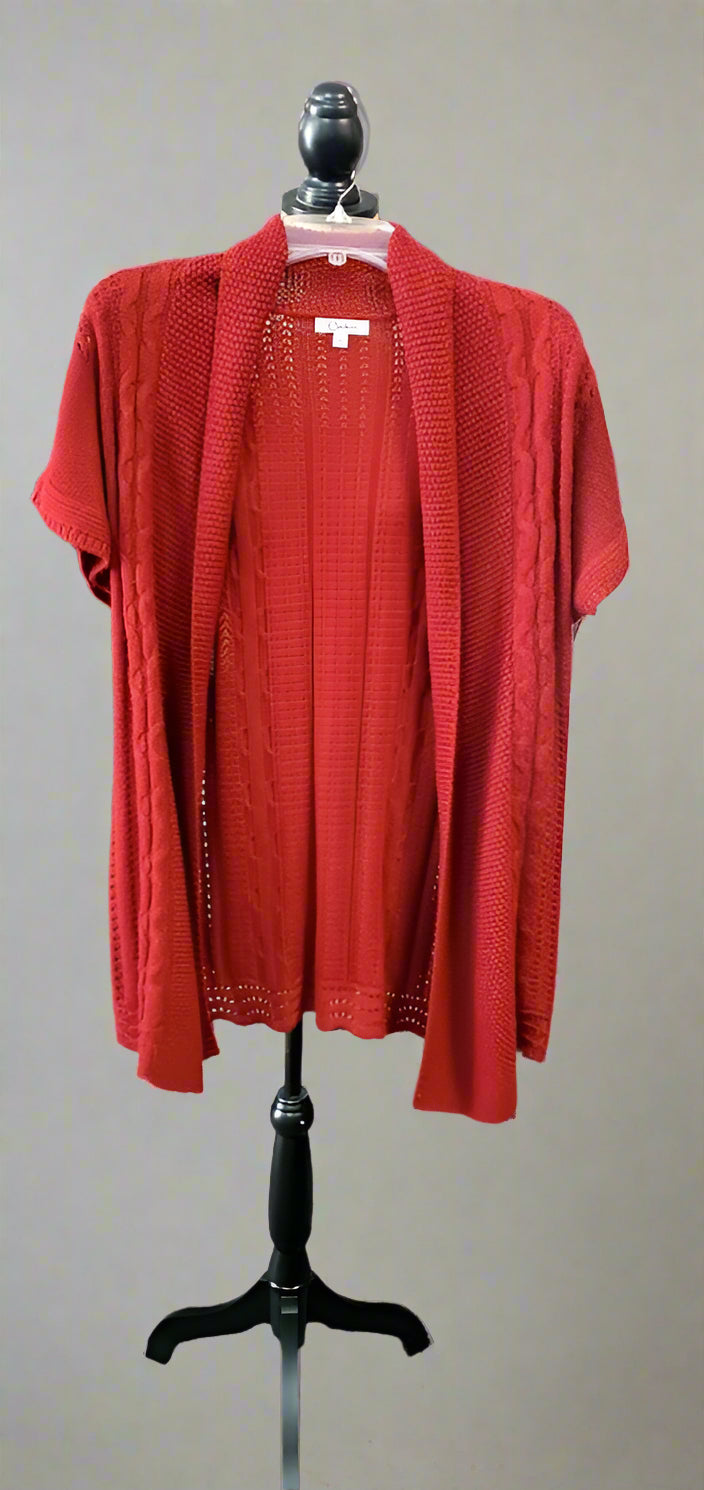 Red cardigan on a black mannequin stand in a clothing store